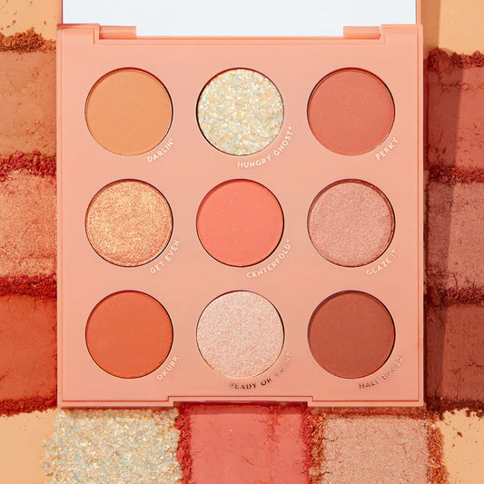A ColourPop shadow palette containing nine shades ranging from matte to glitter finishes, with hues in oranges, corals, neutrals, and golds.